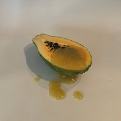 Organically Kismet Pure Gold Sea Moss Gel poured into a halved papaya, with the golden gel flowing over the fruit onto a clean surface
